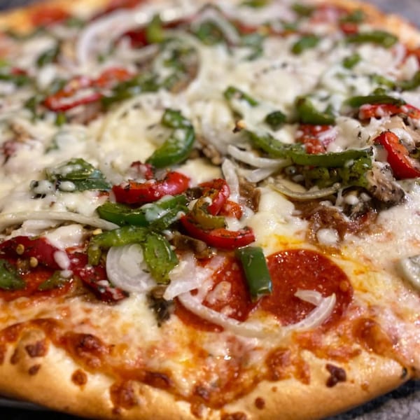Close-up of a Ray's Pizza with pepperoni, green peppers, red peppers, and onions.
